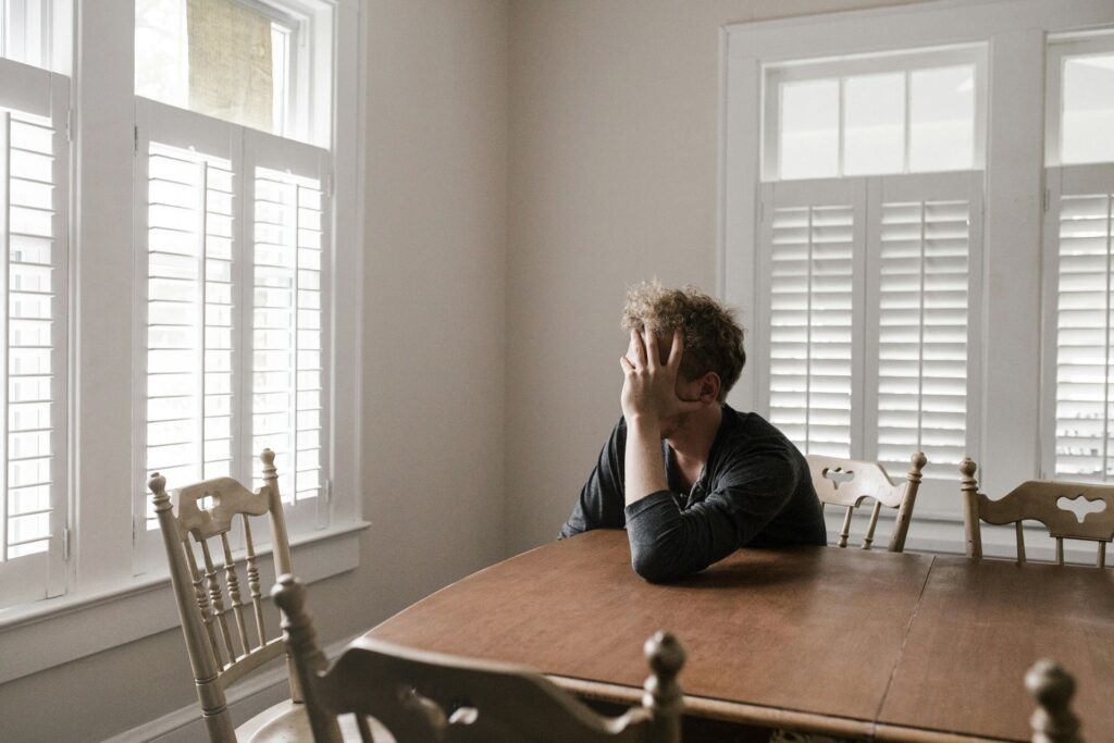 a man alone at a table, contemplating anxiously